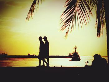 Silhouette of people on beach at sunset