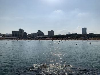 Sea by buildings against sky in city