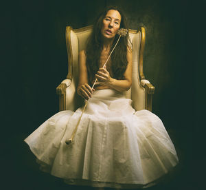 Woman in white skirt sitting in an antique armchair iii