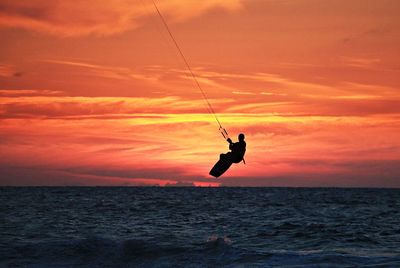 Silhouette person in sea against sky during sunset