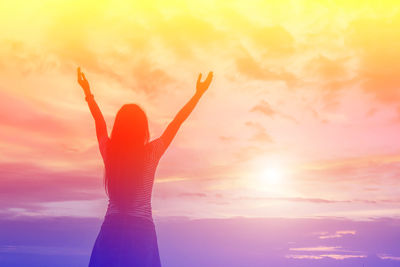 Silhouette woman with arms raised against sky during sunset