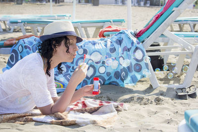 Beautiful woman blowing soap bubbles at the beach, close up portrait