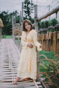 Portrait of smiling young woman standing against plants