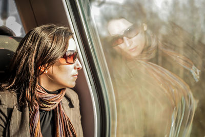 Beautiful woman wearing sunglasses looking through window while sitting in car