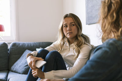 Daughter talking to mother while sitting at home