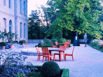 Empty chairs and tables in park against buildings in city
