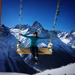 Full length of man on snowcapped mountains against blue sky