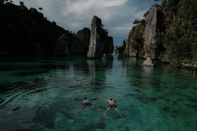 People swimming in sea against sky