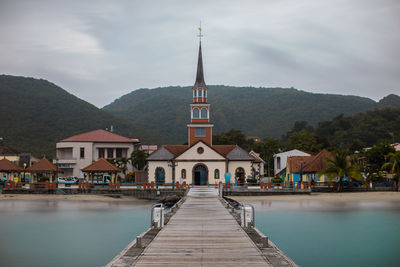 View of pier in sea by buildings against sky