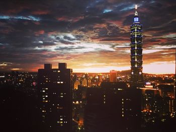 Illuminated cityscape against sky at sunset