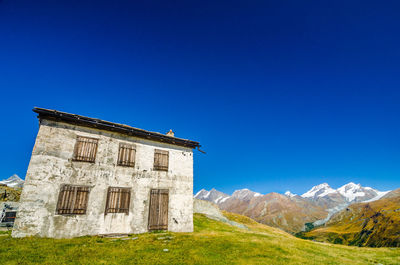 Built structure on landscape against clear blue sky