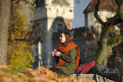 Young woman sitting on retaining wall