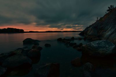 Rocks by sea against sky during sunset