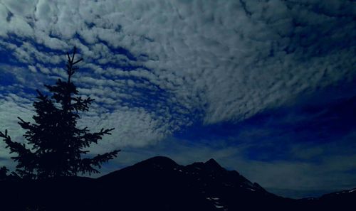 Low angle view of silhouette mountains against sky at night