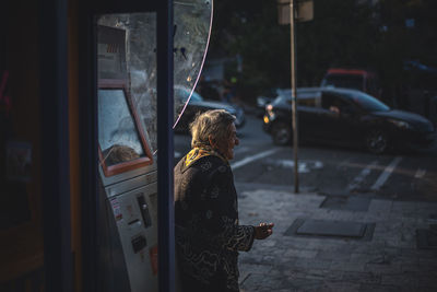 Rear view of woman standing on street in city