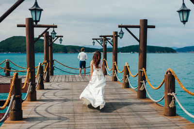 Rear view of people on pier over sea against sky