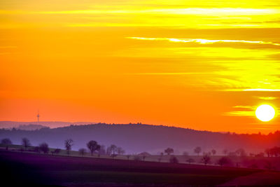 Scenic view of field against orange sky