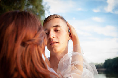 Portrait of young woman against sky