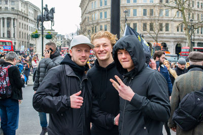 Portrait of friends standing on street in city