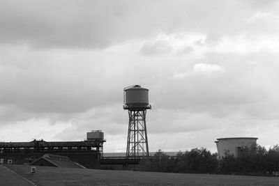 Water tower against cloudy sky