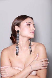 High end fashion  head shot of brunette model wearing long shiny earrings, professional make up