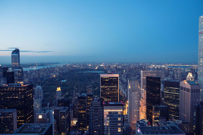 Aerial view of city lit up against blue sky