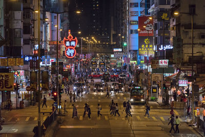 People on city street amidst buildings at night