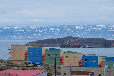 Buildings by sea against sky