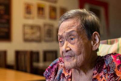 Close-up of thoughtful senior woman looking away while sitting at home