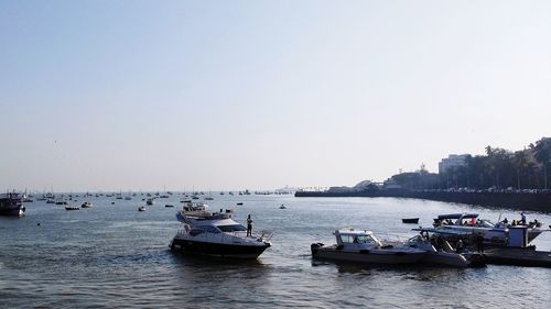 Boats moored in sea against clear sky