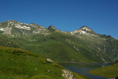 Scenic view of lake and mountains against clear blue sky