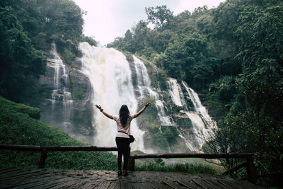 Full length of woman standing against waterfall