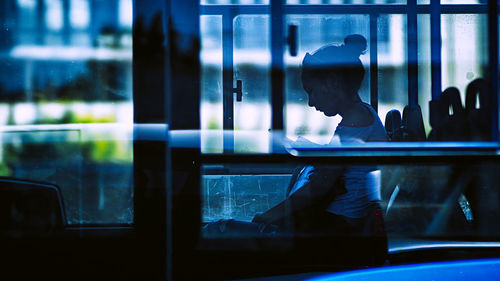 Woman using mobile phone seen through bus window