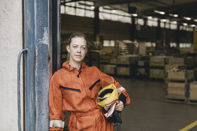 Portrait of female blue-collar worker in uniform standing at factory doorway