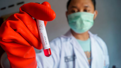 Scientist wearing mask holding test tube in laboratory