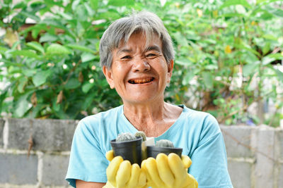 Smiling senior woman holding plants