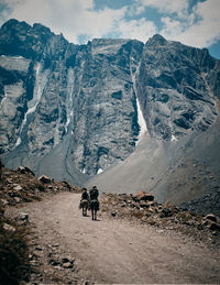 People walking on snowcapped mountain against sky