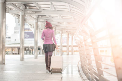 Rear view of woman pulling bag at airport