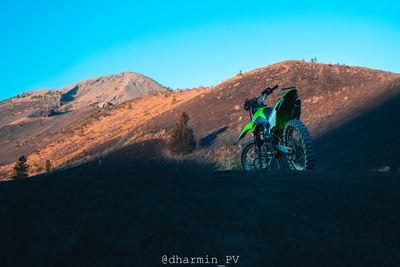 Man riding bicycle on road against mountain