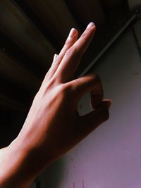 Close-up of hand with ok sign against wall