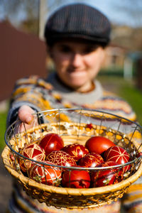Closeup of basket of colored red eggs, easter holiday concept. young person holding modern painted 