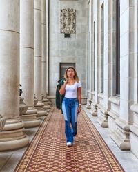 Portrait of young woman standing against building