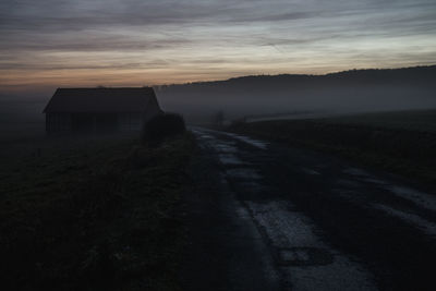 Road amidst agricultural landscape against sky during sunset