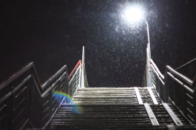 Low angle view of illuminated staircase by building against sky at night