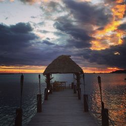 Pier on sea against cloudy sky