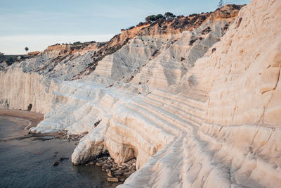 Rock formations by sea at scala dei turchi