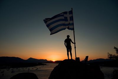 Silhouette man standing at beach against clear sky during sunset