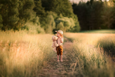 Woman cute boy holding toy while standing on field