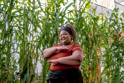 Smiling young woman standing by plants on field