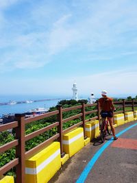 Rear view of man by sea against sky